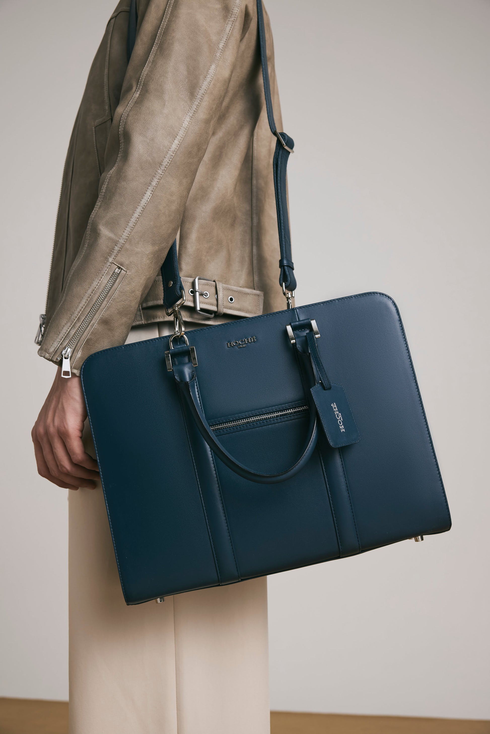 Lifestyle shot of PinnaclePro dark blue leather laptop bag for men carrying it as messenger bag, styled for modern professionals who appreciate elegance and functionality.
